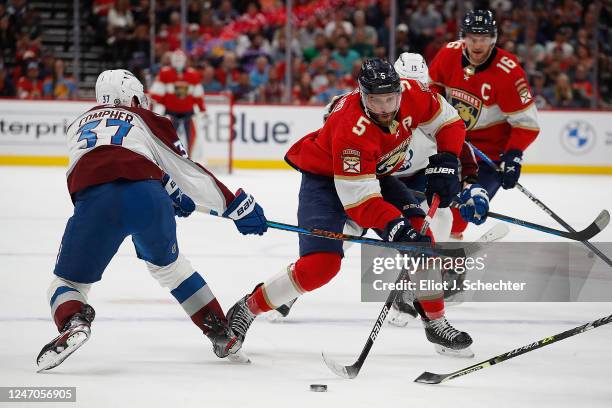 Aaron Ekblad of the Florida Panthers attempts to gather the puck against J.T. Compher of the Colorado Avalanche at the FLA Live Arena on February 11,...