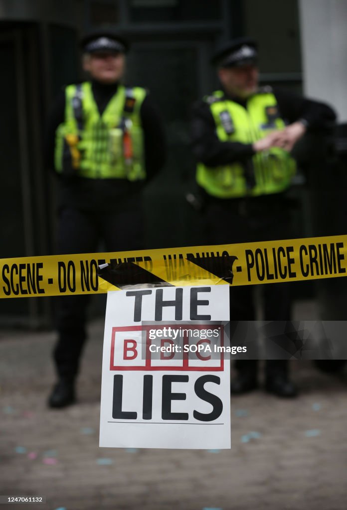 Protesters stick The BBC Lies signs on police tape as...