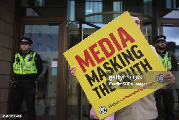 Protester with her face almost completely obscured holds a placard saying Media Masking the Truth as police prevent protesters from approaching the...