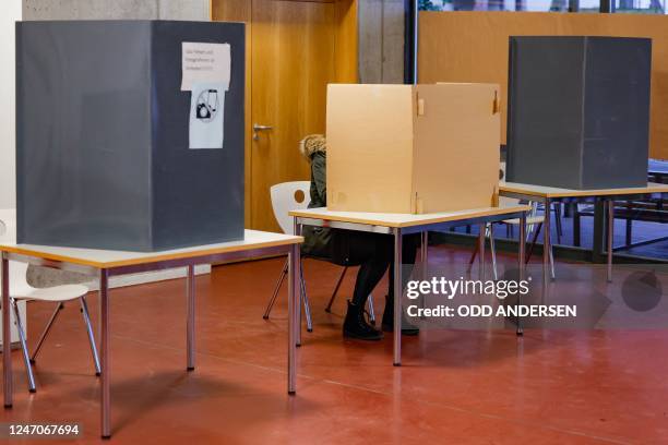 Woman prepares her ballot before casting her vote in the state's repeat elections at a polling station in west Berlin on February 12, 2023. - Berlin...