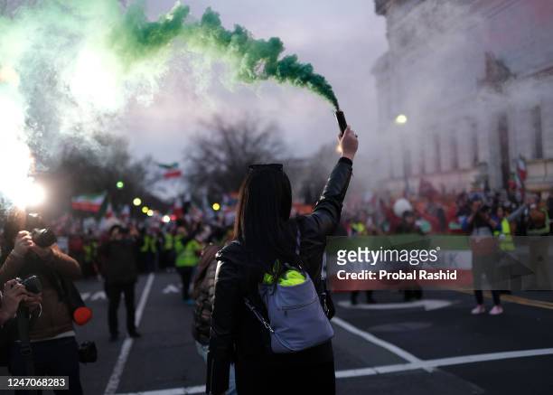 Protester holding a green smoke flare during a demonstration to denounce the Iranian government and express support with anti-government protesters...