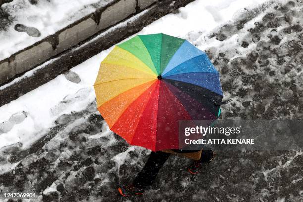 Woman carries an umbrella as she walks along a street during snowfall in the Iranian capital Tehran, on February 12, 2023.