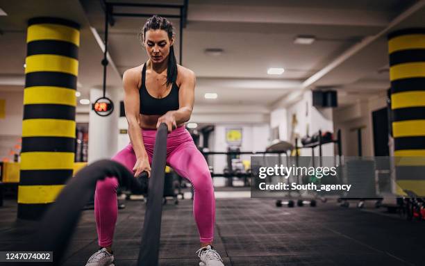 one fit woman working out with battle ropes in the gym - battle rope stock pictures, royalty-free photos & images