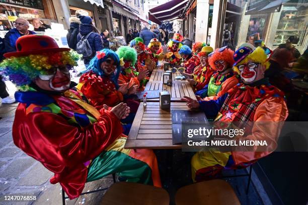 Revellers dressed up as clowns are pictured at a restaurant's terrace in Venice on February 12, 2023 during the Venice carnival.