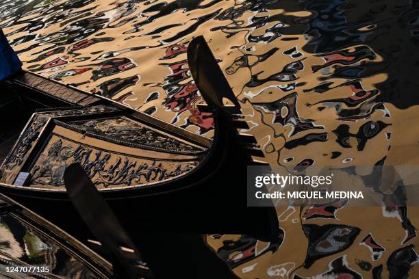 Gondola is pictured with a building reflected in the waters in Venice on February 12, 2023 during the Venice carnival.