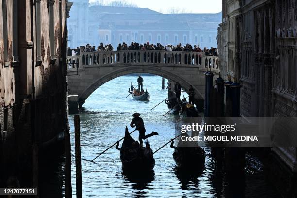 Tourists enjoy a gondola ride under the Ponte della Paglia bridge during the carnival in Venice on February 12, 2023.