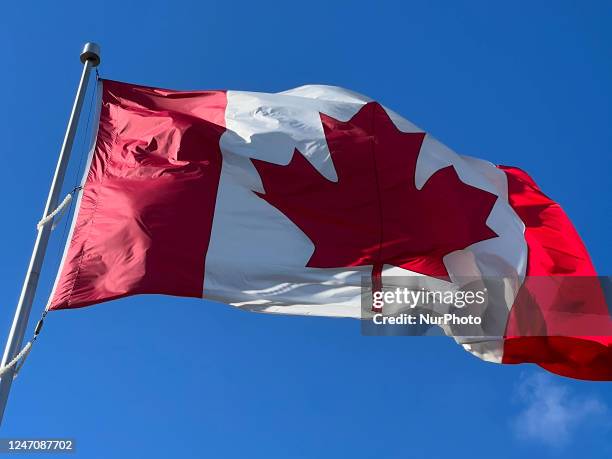 Canadian flag flutters against a blue sky in Richmond Hill, Ontario Canada, on February 11, 2023.