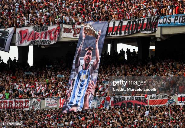 Fans of River Plate hang a flag of FIFA World Cup 2022 champion Lionel Messi before a match between River Plate and Argentinos Juniors as part of...