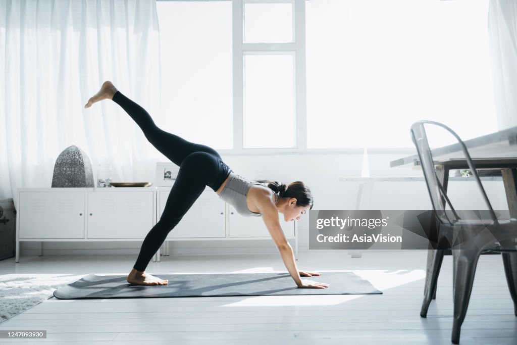 朝、自宅のリビングルームでヨガを練習している若いアジア人女性