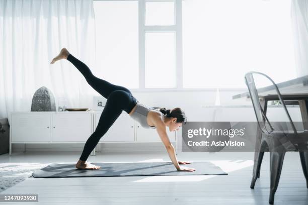 年輕的亞洲女人在客廳練習瑜伽在家裡上午 - 女子体操 個照片及圖片檔