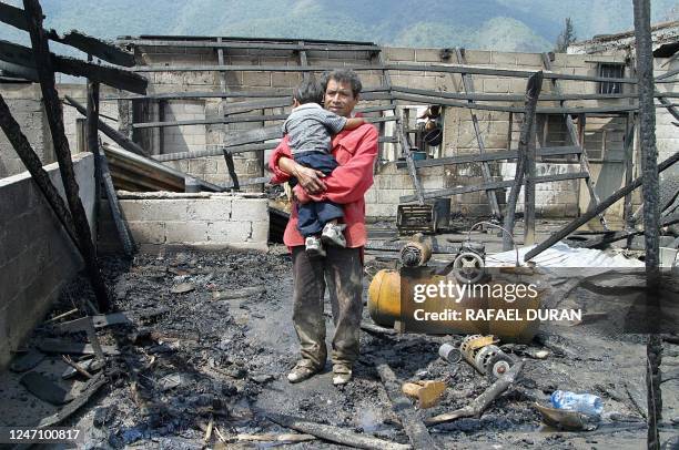 An unidentified man holding his child stands amidst the ruins of houses destroyed by the overflow of the Rio Chiquito, which also caused the...