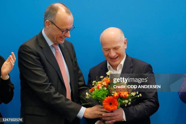 Christian Democratic Union party's top candidate Kai Wegner reacts as he receives a bouquet of flowers from the leader of Germany's conservative...