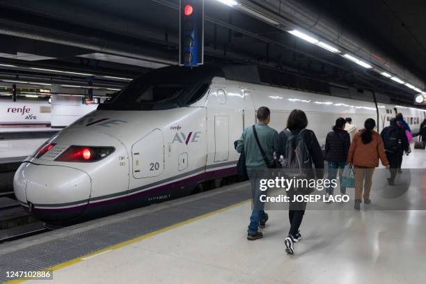 Passengers walk past an AVE high-speed train at Barcelona-Sants railway station prior to departing to Lyon on a test trip along a new international...