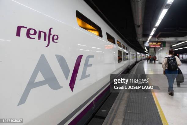 Passengers walk past an AVE high-speed train at Barcelona-Sants railway station prior to departing to Lyon on a test trip along a new international...
