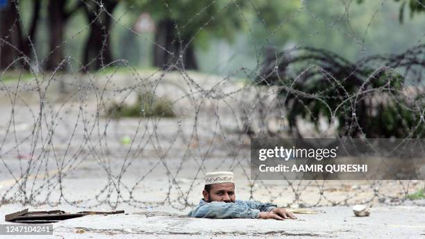 Worker of the Pakistani Gas Company peers out of a hole in the middle of a street near the radical Islamic Red Mosque as authorities ordered to close...