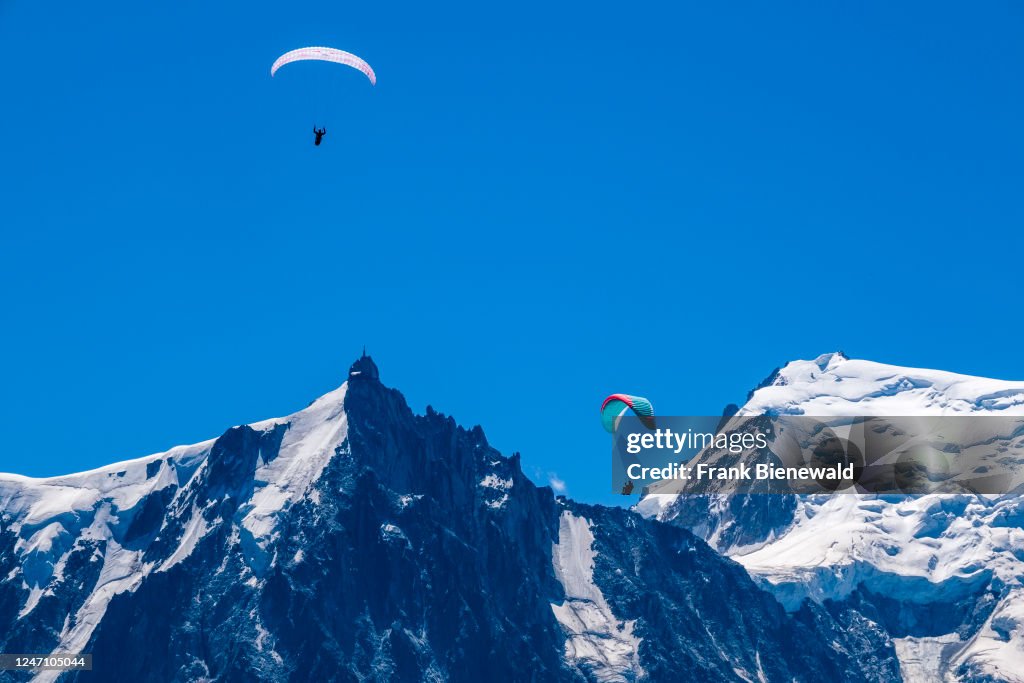 Paragliders fly against the backdrop of the Aiguille du Midi...