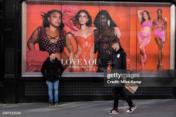 Passers by interact with advertising photographs featuring models of all sizes and mixed ethnicities in the shop windows of exclusive lingerie store...