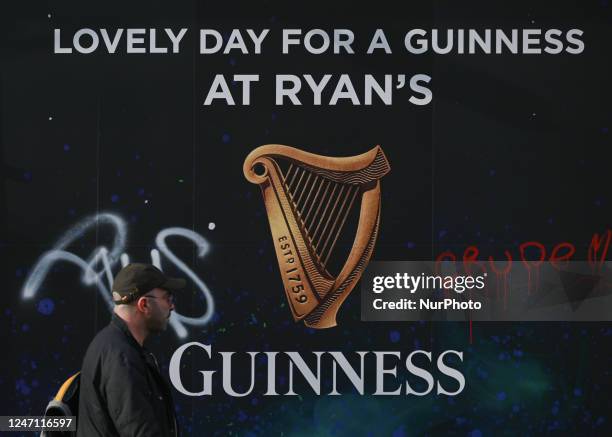 Man runs past a Guinness logo outside Ryan's Pub, in Dublin, Ireland, on February 12, 2023.