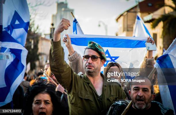 An Israeli reserve soldier raises his fist as he marches during the demonstration. Tens of thousands of protesters waving Israeli flags converged on...