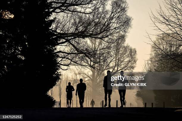 Joggers run in Preston Park, in Brighton, south of England, at sunrise on February 14, 2023.