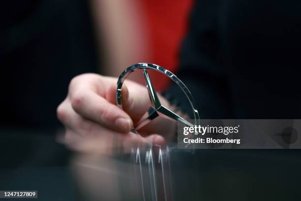 An employee fixes a hood ornament to a Mercedes-Benz S-Class luxury automobile on the assembly line at the Mercedes-Benz Group AG plant in...