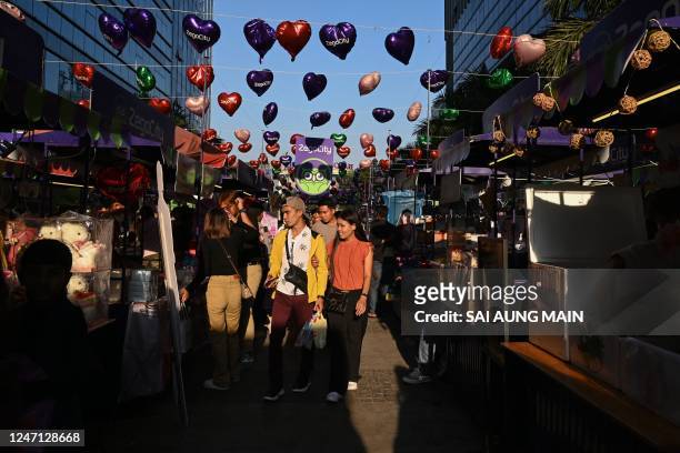 People walk on a street decorated with balloons for Valentines Day in Yangon on February 14, 2023.