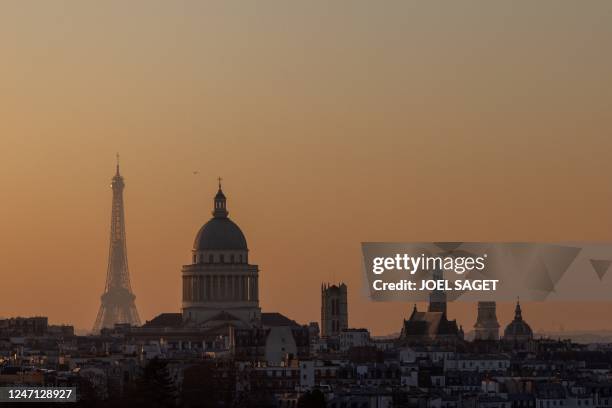 This photograph taken at sunset on February 13, 2023 in Paris shows the Eiffel tower and the dome of the Pantheon, the mausoleum reserved for...