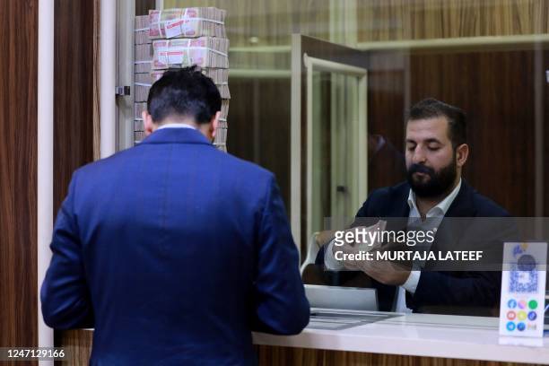 An employee counts banknotes at currency exchange shop in Baghdad on February 14, 2023. - Iraq nudged up the value of its local currency against the...