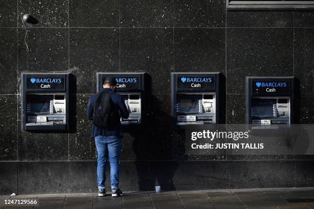 Customer uses an ATM machine, outside a branch of British bank Barclays, in central London, February 14, 2023.