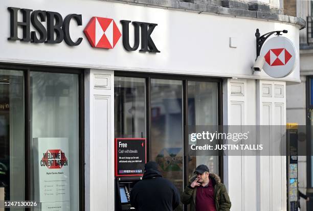 Customer uses an ATM machine outside a branch of HSBC bank, in central London, February 14, 2023.