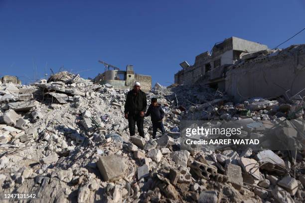 Syrian man who lost most of his family members in last week's earthquake, walks with one of his surviving sons above the rubble of their collapsed...