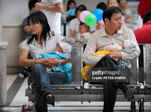 Mother and a father hold their babies as they wait for treatment in a children's hospital in Beijing on September 23, 2008 as China's toxic milk...