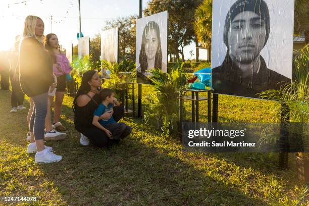 Mariana Rocha , holds her son Jackson as she observes a photo of her cousin Joaquin Oliver at a memorial on the fifth anniversary of the Marjory...