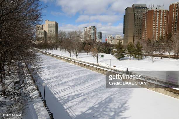 Jogger runs along the snow covered Rideau Canal on February 8, 2023 in Ottawa, Canada. - This winter has brought wild and unseasonably warm weather...