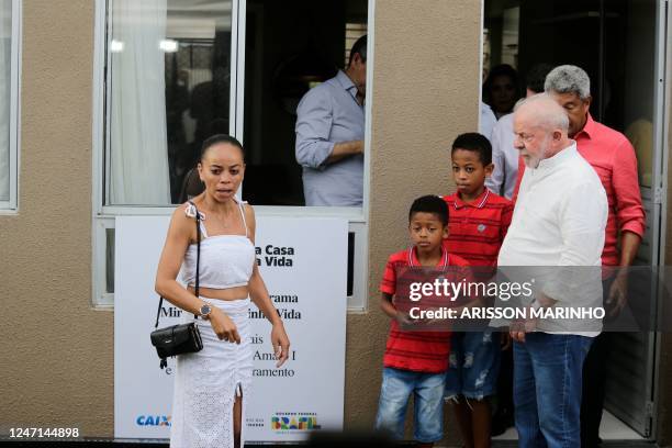 Brazil's President Luiz Inacio Lula da Silva stands next to a woman and her sons after they received the key to their new house during an event...