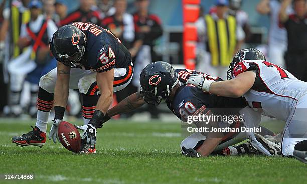 Brian Urlacher of the Chicago Bears pics up a fumble that's out of the reach of teammate Julius Peppers as Sam Baker of the Atlanta Falcons holds...