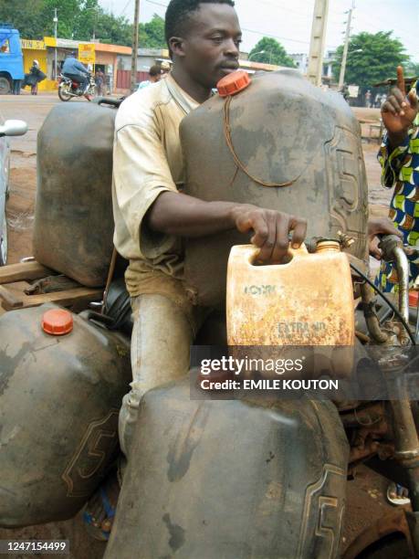 An illegal gasoline vendor fills a container 03 June 2006 in the town of Porto Novo, 30 kms east of the capital Cotonou. Benin has delayed...