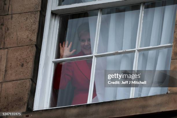 Nicola Sturgeon waves from a window, after holding a press conference, as people gather outside of Bute House on February 15, 2023 in Edinburgh,...