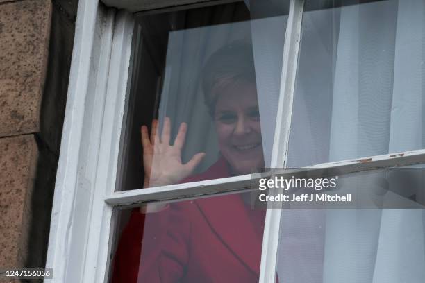 Nicola Sturgeon waves from a window, after holding a press conference, as people gather outside of Bute House on February 15, 2023 in Edinburgh,...