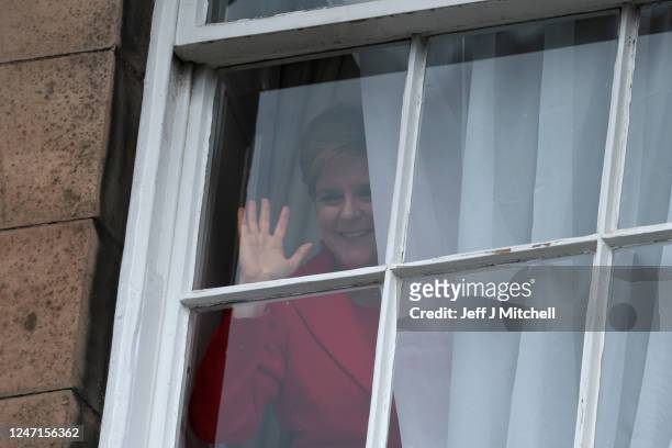 Nicola Sturgeon waves from a window, after holding a press conference, as people gather outside of Bute House on February 15, 2023 in Edinburgh,...