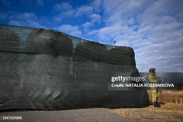 Belarusian border guard keeps watch standing by a barricade made of truck tyres at the Divin border crossing point between Belarus and Ukraine in the...