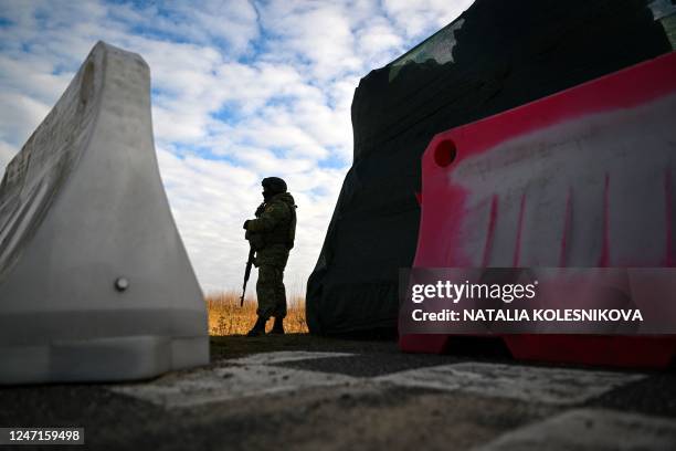 Belarusian border guard keeps watch standing by a barricade made of truck tyres at the Divin border crossing point between Belarus and Ukraine in the...