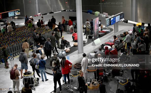 Passengers await for their luggage at a carousel upon arriving at Charles de Gaulle airport in the Paris suburb of Roissy on February 15, 2023.