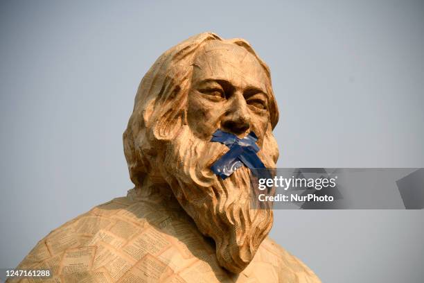 Protest sculpture that depicts Poet Rabindranath Tagore with his mouth taped and holding a book that has been closed by a nail is set on the foot of...