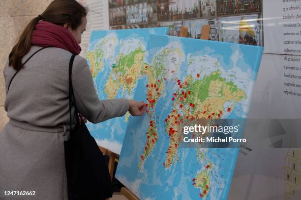 Protester places red pins on a map of the world showing the Shell operations before a fake boardroom meeting outside the Dutch Shell offices during...