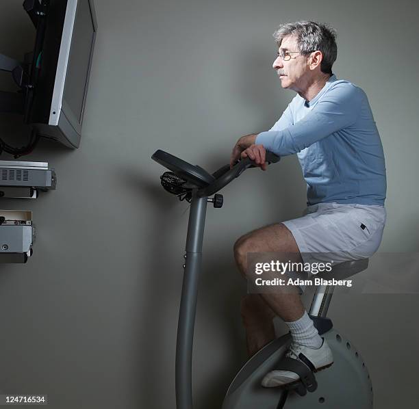 baby boomer on stationary bicycle - dvd speler stockfoto's en -beelden