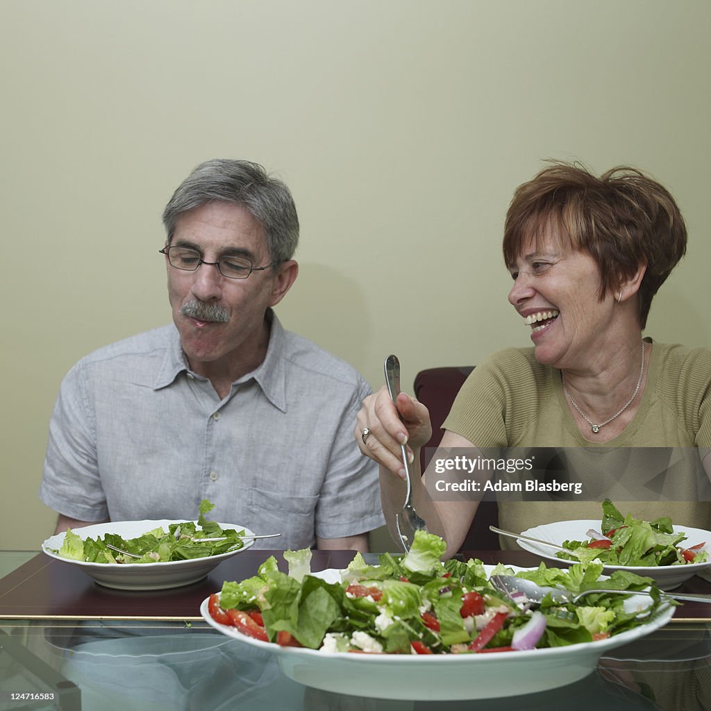 Baby boomer couple eating salad at dinner table
