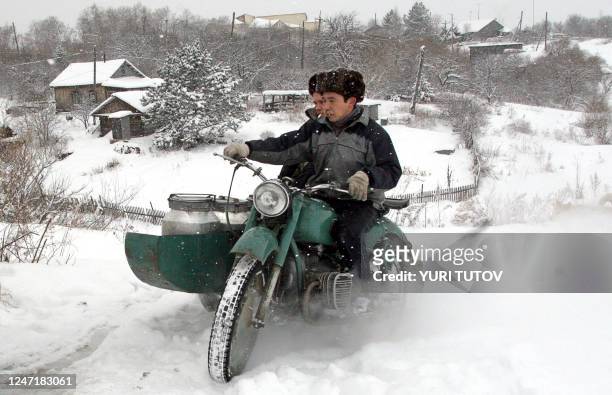 Two men ride a motorcycle with churns of clean water in the village of Sikachi-Olyan some 60 km outside Khabarovsk, 03 December 2005. Russian experts...