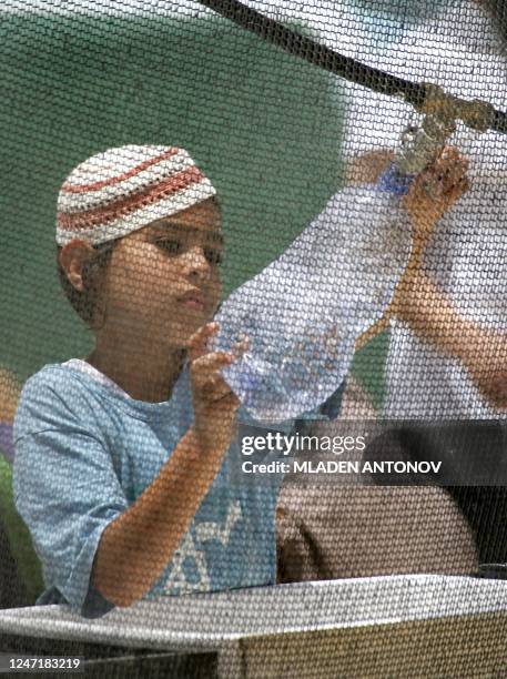 An Israeli settler boy fills a bottle with fresh water at a makeshift hut erected to house opponents to Israel's planned disengagement plan, along...