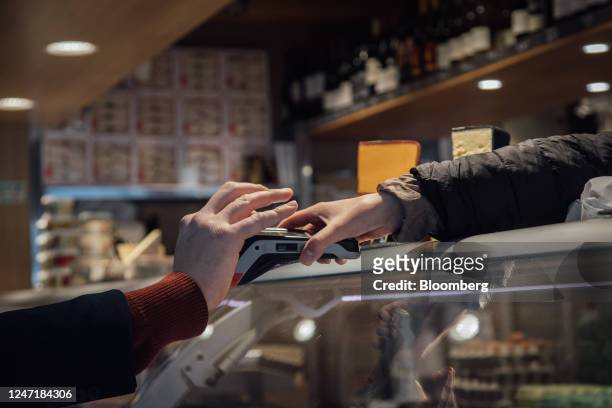 Customer uses a bank card at a contactless payment terminal on a stall in the Bauveau Market in Paris, France, on Wednesday, Feb. 15, 2023. French...